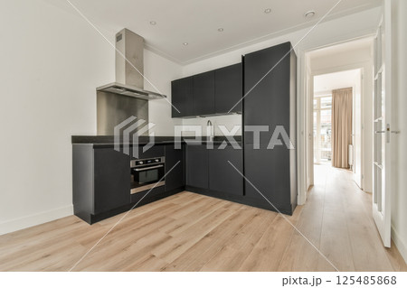 A sleek and modern kitchen featuring minimalistic design with dark cabinets, a shiny countertop, and a bright entrance leading to natural light. A sleek and modern kitchen featuring minimalistic design with dark cabinets, a shiny countertop, and a bright entrance leading to natural light. 125485868