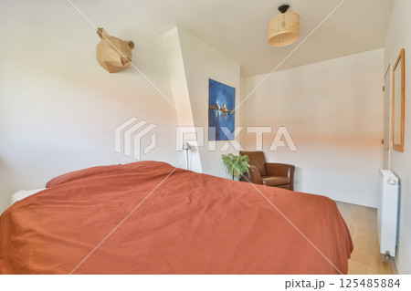 A well-designed bedroom with minimalistic decor featuring a warm color scheme, a comfortable bed, and contemporary artwork on the wall. A well-designed bedroom with minimalistic decor featuring a warm color scheme, a comfortable bed, and contemporary artwork on the wall. 125485884