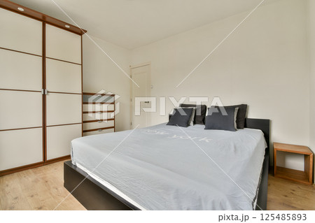 Sleek modern bedroom featuring a stylish bed, neutral-toned walls, and organized storage cabinetry, creating a serene and functional space. Sleek modern bedroom featuring a stylish bed, neutral-toned walls, and organized storage cabinetry, creating a serene and functional space. 125485893