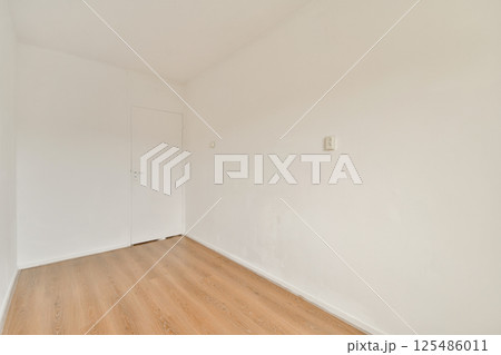 A clean and minimalist interior space featuring plain white walls and a wooden floor, exuding simplicity and openness. Ideal for modern decor concepts. 125486011