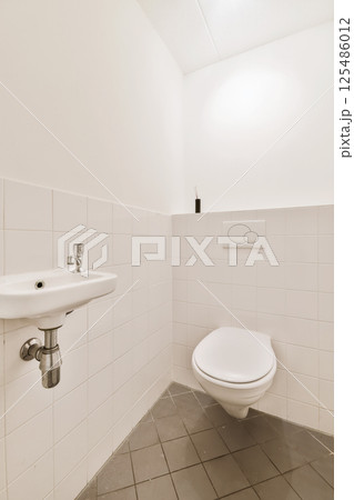 a bathroom with a sink and toilet paper dispensed on the wall next to it is a mirror 125486012