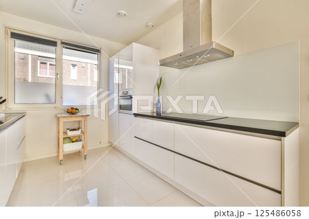 A sleek, modern kitchen featuring white cabinetry, minimalist decor, and stylish appliances. The bright, open layout is ideal for contemporary living. 125486058