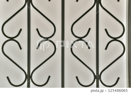 A detailed pattern of black metalwork against a translucent background, showcasing curves and elegance in design that enhances aesthetic appeal. 125486065