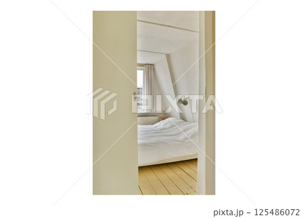 A glimpse into a cozy, modern bedroom featuring a minimalistic design with a white bedspread and natural light streaming through the window. A glimpse into a cozy, modern bedroom featuring a minimalistic design with a white bedspread and natural light streaming through the window. 125486072