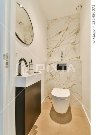 Elegant and minimalist bathroom featuring a sleek vanity, modern toilet, and marble walls for a luxurious ambiance. Elegant and minimalist bathroom featuring a sleek vanity, modern toilet, and marble walls for a luxurious ambiance. 125486073