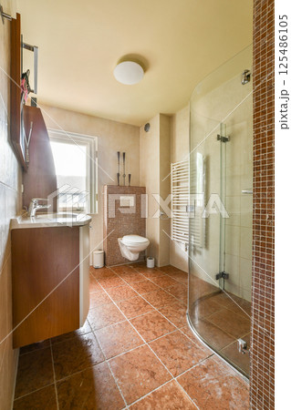 Contemporary bathroom featuring elegant tiles, a glass shower, modern fixtures, and a bright atmosphere. Ideal for showcasing stylish interiors. Contemporary bathroom featuring elegant tiles, a glass shower, modern fixtures, and a bright atmosphere. Ideal for showcasing stylish interiors. 125486105