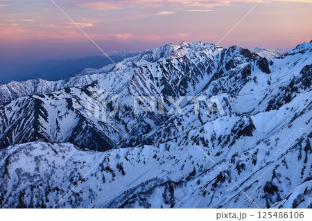 夕焼けの冠雪の北アルプスの後立山連峰 125486106