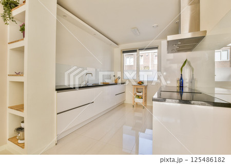 Sleek and minimalistic kitchen design featuring white cabinetry, spacious layout, and natural light streaming through large windows, creating a bright atmosphere. Sleek and minimalistic kitchen design featuring white cabinetry, spacious layout, and natural light streaming through large windows, creating a bright atmosphere. 125486182
