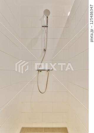 A clean and modern shower area featuring sleek white tiles and simple fixtures, emphasizing minimal design elements for a refreshing ambience. 125486347