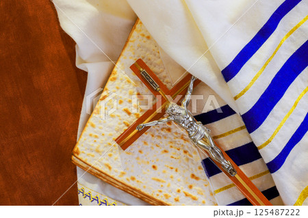 Crucifix on matzo bread, draped in tallit prayer shawl ceremonial cloth, symbolizes religious meaning at festivity. Crucifix on matzo bread, draped in tallit prayer shawl ceremonial cloth, symbolizes religious meaning at festivity. 125487222