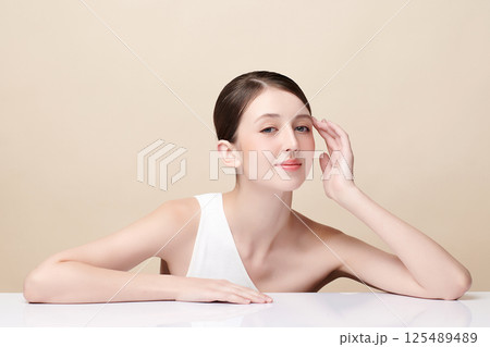 A beautiful young woman with clean, fresh skin against a beige background. Skincare, facial treatment, cosmetology, beauty, and spa. An elegant portrait of an woman. A beautiful young woman with clean, fresh skin against a beige background. Skincare, facial treatment, cosmetology, beauty, and spa. An elegant portrait of an woman. 125489489