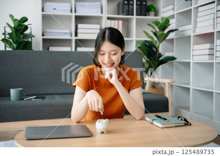 Women are putting coins in a piggy bank for a business that grows for profit and saving money for the future. planning for retirement concept 125489735