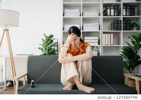 Asian woman sit Depression Dark haired  pensive glance Standing by window and anxiety Copy space. 125489746