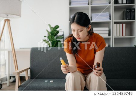 Asian Woman sitting in the sofa with a large number of pills Depressed woman wants to kill herself by drug overdose, depression concept. Asian Woman sitting in the sofa with a large number of pills Depressed woman wants to kill herself by drug overdose, depression concept. 125489749