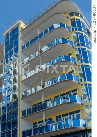 Facade of a multi story building with mirrored windows and balconies. Facade of a multi story building with mirrored windows and balconies. 125490637