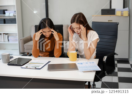 Businesswoman team working are under stress from financial data and report graph. Businesswoman team working are under stress from financial data and report graph. 125491315
