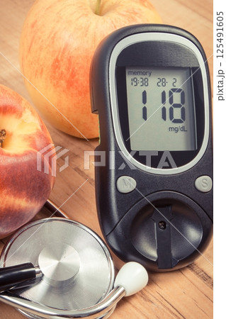 Glucometer with sugar level and fresh fruits. Healthy lifestyle and nutrition during diabetes Glucometer with sugar level and fresh fruits. Healthy lifestyle and nutrition during diabetes 125491605