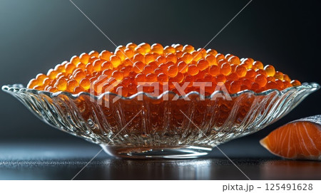Delicious bowl of bright orange fish roe displayed artistically against a dark background creating an enticing food experience 125491628