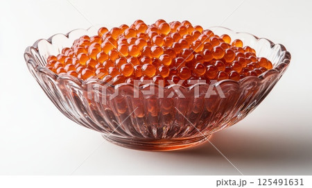 Details showcase vibrant salmon roe presented in an elegant glass bowl with intricate design against a clean, minimalistic backdrop 125491631