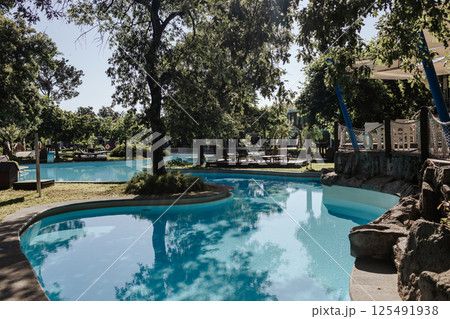 An elegant tropical resort with shady gardens and a winding pool surrounded by greenery. Turquoise water and a warm atmosphere of relaxation. An elite resort complex with crystal clear water. An elegant tropical resort with shady gardens and a winding pool surrounded by greenery. Turquoise water and a warm atmosphere of relaxation. An elite resort complex with crystal clear water. 125491938