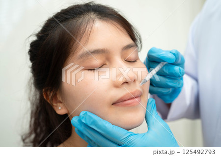 Asian woman receiving plastic surgery shape of nose performed on face. 125492793