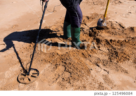 Treasure hunt on sandy beach with metal detector and shovel 125496084