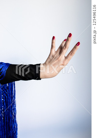 Caucasian female hand with red nails gesturing in black and blue outfit 125496116