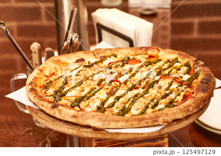 There is a round delicious pizza on the table in a cafe. There is a round delicious pizza on the table in a cafe. 125497129