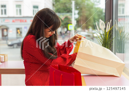 Woman exploring purchases in colorful shopping bags. Concept of consumption and lifestyle leisure Woman exploring purchases in colorful shopping bags. Concept of consumption and lifestyle leisure 125497145