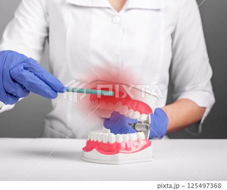 Gum inflammation. Woman pointing to mouth with red painful gingiva, showing dental disease, bleeding Gum inflammation. Woman pointing to mouth with red painful gingiva, showing dental disease, bleeding 125497368