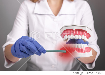 Gum inflammation. Woman with painful red gingiva pointing to mouth, showing dental disease, bleeding 125497369