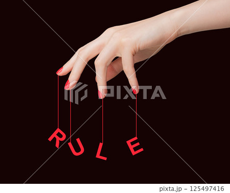 Rule and manipulation concept with female hand. Red nail fingers holding string, control, authority, 125497416