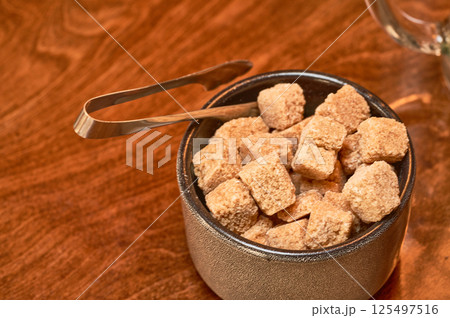 Brown cane sugar in a cup on a wooden table.  125497516