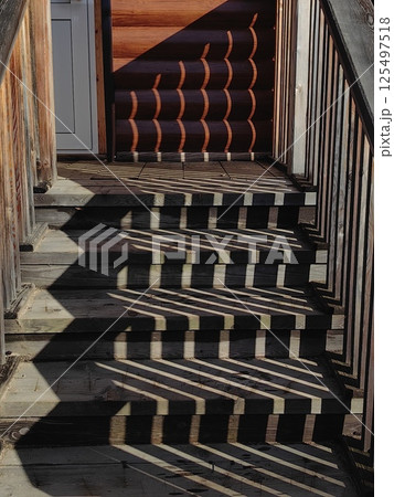 abstract unique patterns shadows created by wooden stair in rustic setting during daytime. 125497518