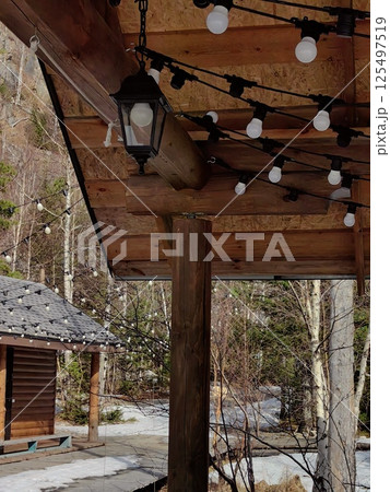 charming outdoor setting string lights and rustic cabin during winter day in serene forest location. charming outdoor setting string lights and rustic cabin during winter day in serene forest location. 125497519