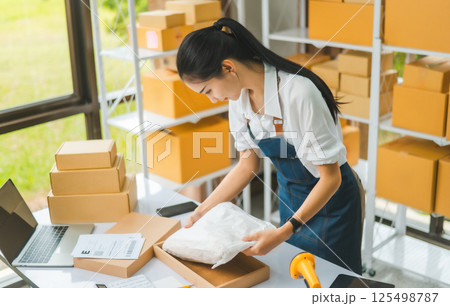 Online small business owners are packing their ordered products that customers order online into a box .concept of online shopping Online small business owners are packing their ordered products that customers order online into a box .concept of online shopping 125498787