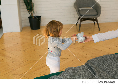 Little child giving mug to parent at home. Care, love and family bonding concept. Little child giving mug to parent at home. Care, love and family bonding concept. 125498886