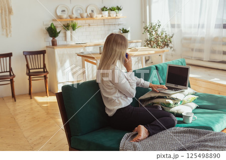 Woman talking on smartphone while working remotely. Communication, freelance and modern home lifestyle theme. 125498890