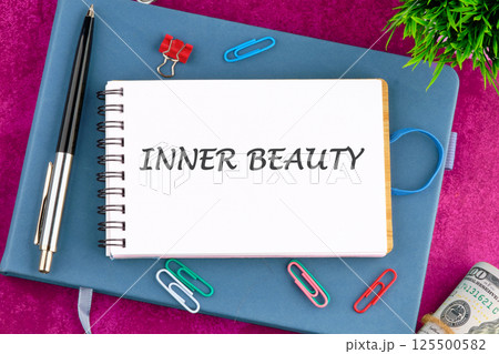 A notebook with the phrase inner beauty prominently displayed sits on a vibrant purple surface A notebook with the phrase inner beauty prominently displayed sits on a vibrant purple surface 125500582
