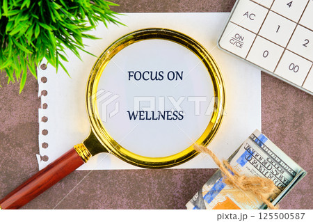 A magnifying glass highlights the phrase focus on wellness placed on a surface with a small plant and nearby items including notes and currency that symbolize self-care and financial wellness A magnifying glass highlights the phrase focus on wellness placed on a surface with a small plant and nearby items including notes and currency that symbolize self-care and financial wellness 125500587