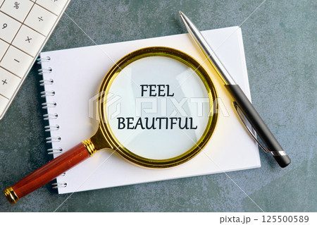 A magnifying glass rests over a notepad, focusing on the words feel beautiful. A pen is placed nearby, creating a serene atmosphere perfect for inspiration and reflection A magnifying glass rests over a notepad, focusing on the words feel beautiful. A pen is placed nearby, creating a serene atmosphere perfect for inspiration and reflection 125500589