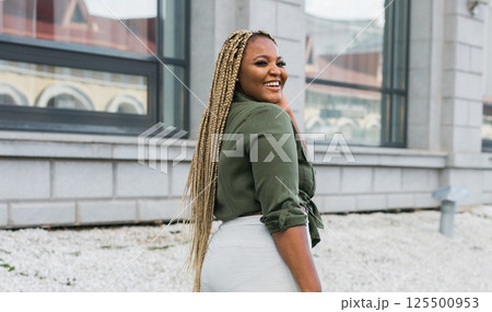 African american smiling woman looking back in the city streets. Joy, confidence, and positive emotions in an urban environment. 125500953