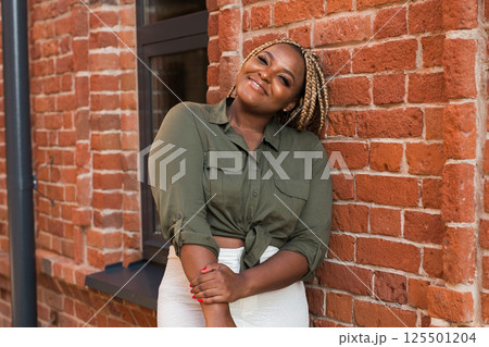 African american woman laughing joyfully while standing on a city street on a sunny day. Freedom, positivity, and happiness in an urban environment African american woman laughing joyfully while standing on a city street on a sunny day. Freedom, positivity, and happiness in an urban environment 125501204