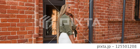 African american woman laughing joyfully while standing on a city street on a sunny day. Freedom, positivity, and happiness in an urban environment. Banner with copy space African american woman laughing joyfully while standing on a city street on a sunny day. Freedom, positivity, and happiness in an urban environment. Banner with copy space 125501208