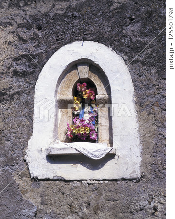 イタリア アングイッラーラ旧市街地の古い岩壁に祀られた聖母マリア像 125501798