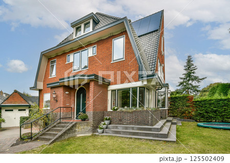 A contemporary brick house featuring large windows, a neatly landscaped lawn, and a minimalist design. Includes outdoor stairs and a serene environment. 125502409