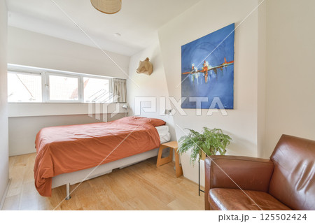 A contemporary bedroom featuring a cozy bed, elegant decor, and natural light filtering through the windows. Ideal for relaxation and comfort in a minimalist setting. A contemporary bedroom featuring a cozy bed, elegant decor, and natural light filtering through the windows. Ideal for relaxation and comfort in a minimalist setting. 125502424