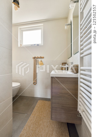 The image showcases a contemporary bathroom featuring sleek designs, natural light, and warm accents, emphasizing both functionality and aesthetics. 125502557
