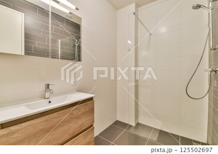 Sleek and contemporary bathroom featuring elegant fixtures, minimalist cabinetry, and bright tile design. A perfect blend of style and functionality in a modern space. 125502697