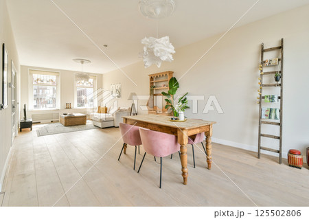 A beautifully designed modern living room featuring minimalistic decor, a wooden table, stylish seating, and warm lighting enhancing the inviting atmosphere. A beautifully designed modern living room featuring minimalistic decor, a wooden table, stylish seating, and warm lighting enhancing the inviting atmosphere. 125502806